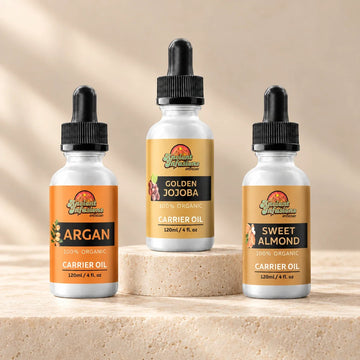 Ancient Infusions Argan, Golden Jojoba, and Sweet Almond carrier oil bottles on ivory stone