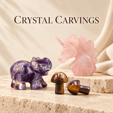 Amethyst elephant, rose quartz unicorn and tiger’s eye mushroom carvings on ivory stone.