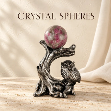 Crystal sphere displayed on an owl pedestal on warm ivory stone.