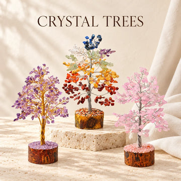 Chakra, amethyst and rose quartz crystal trees on ivory stone.