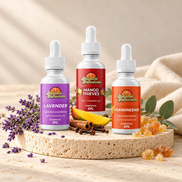 Ancient Infusions Lavender, Mango Thieves, and Frankincense essential oil bottles on an ivory stone display