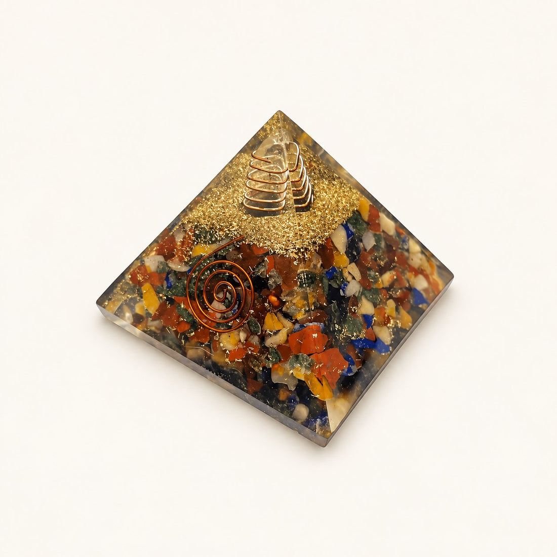 7 Chakra Orgone Pyramid – Mixed Crystal with mixed-color crystal chips and metallic details on a warm ivory background