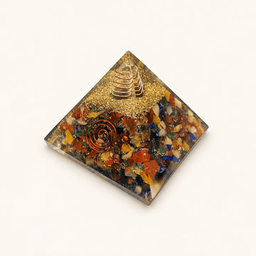 7 Chakra Orgone Pyramid – Mixed Crystal with mixed-color crystal chips and metallic details on a warm ivory background