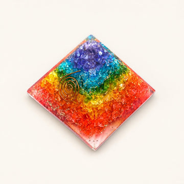 7 Chakra Orgone Pyramid – Rainbow with rainbow crystal layers and metallic details on a warm ivory background