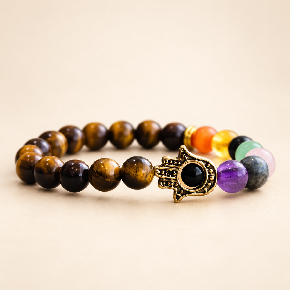 7 Chakra Tiger’s Eye Hamsa Elastic Bracelet on a soft ivory background, view 1