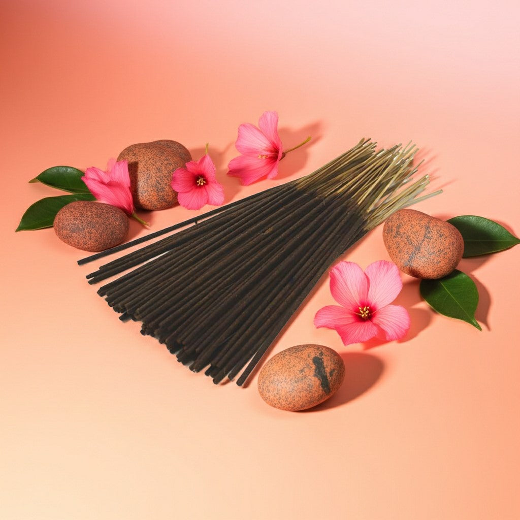 Grapefruit Incense Sticks with a pink ribbon on a pink background with stones and leaves.