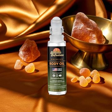 Amber Gold Body Oil roll-on with golden amber stones and luxurious silk background.