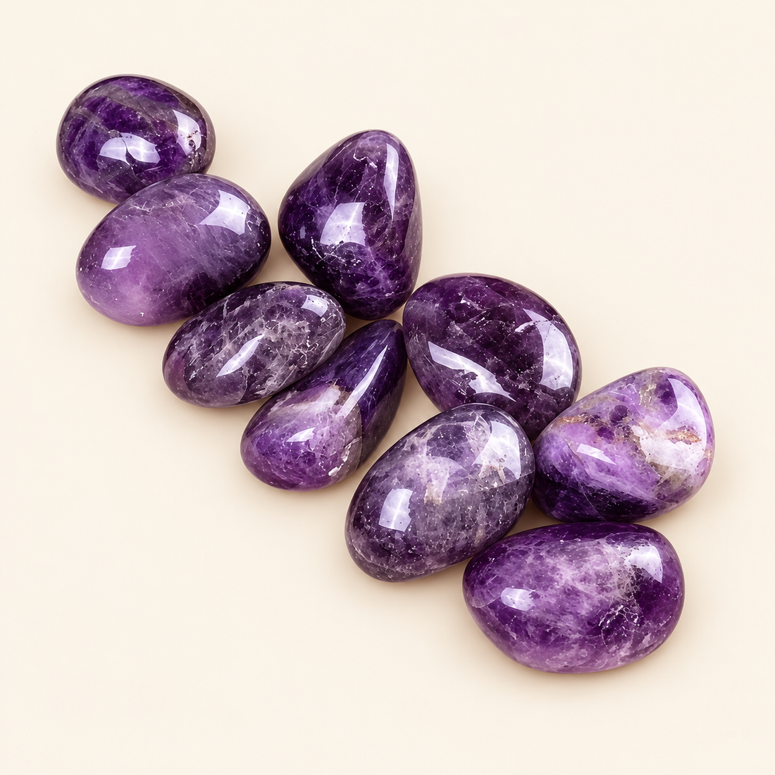 Amethyst tumbled stones with rich purple tones on a soft ivory background