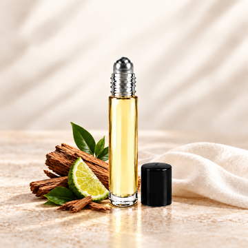 Slim glass perfume oil bottle with a silver roller top and black cap beside cedarwood and bergamot.