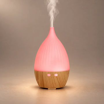 Teardrop ultrasonic aroma diffuser with a pink LED cover, wood grain base and visible cool mist.