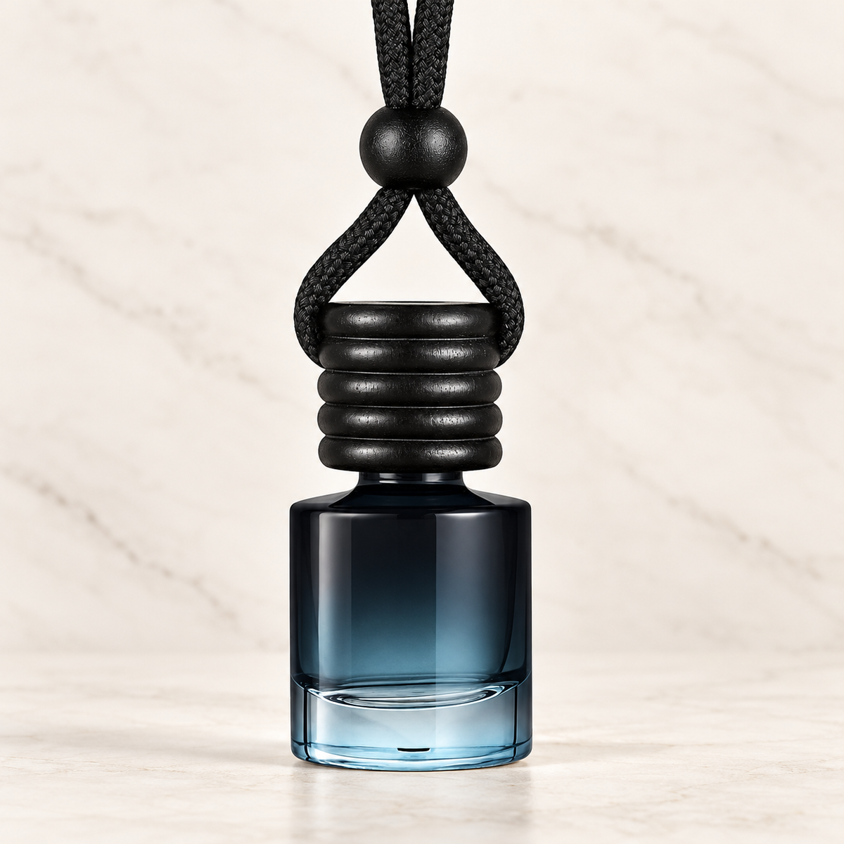 Ancient Infusions hanging car diffuser with smoky blue glass bottle, black cap and cord on ivory stone