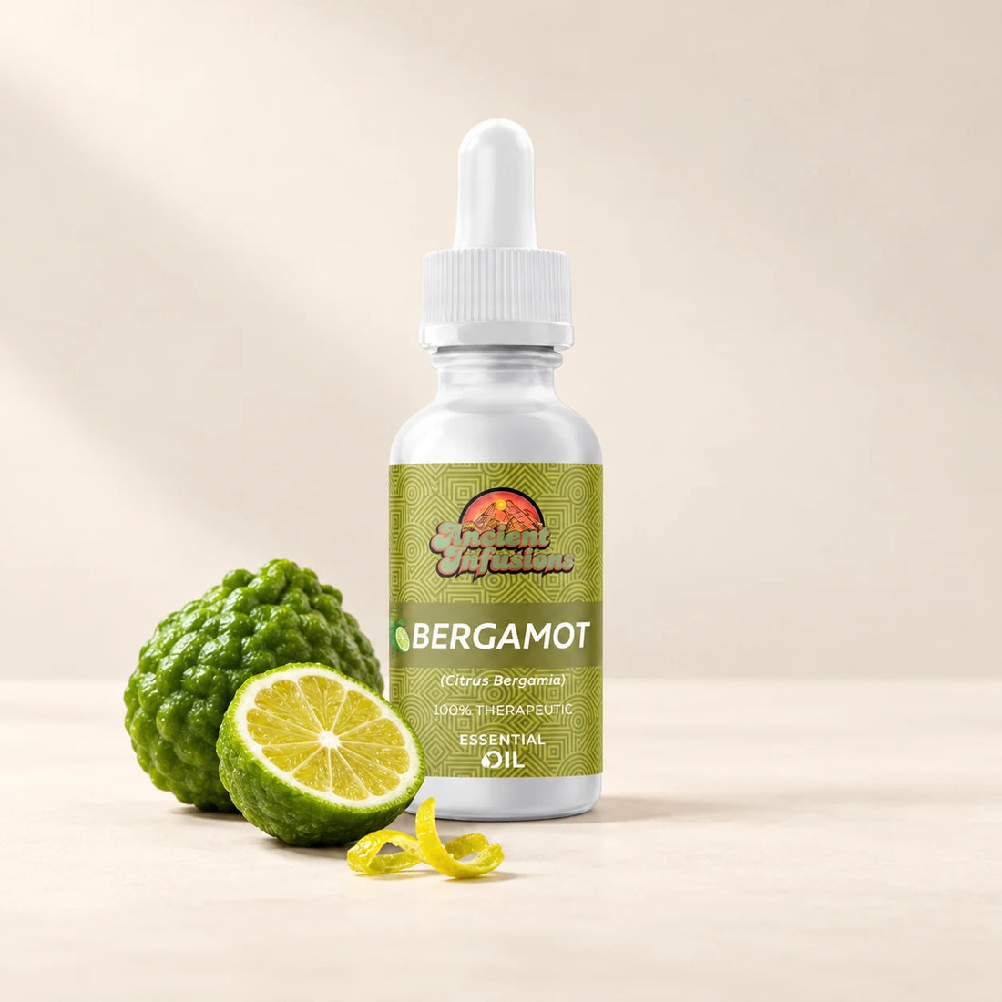Ancient Infusions Bergamot Essential Oil bottle with botanicals on a soft ivory background.