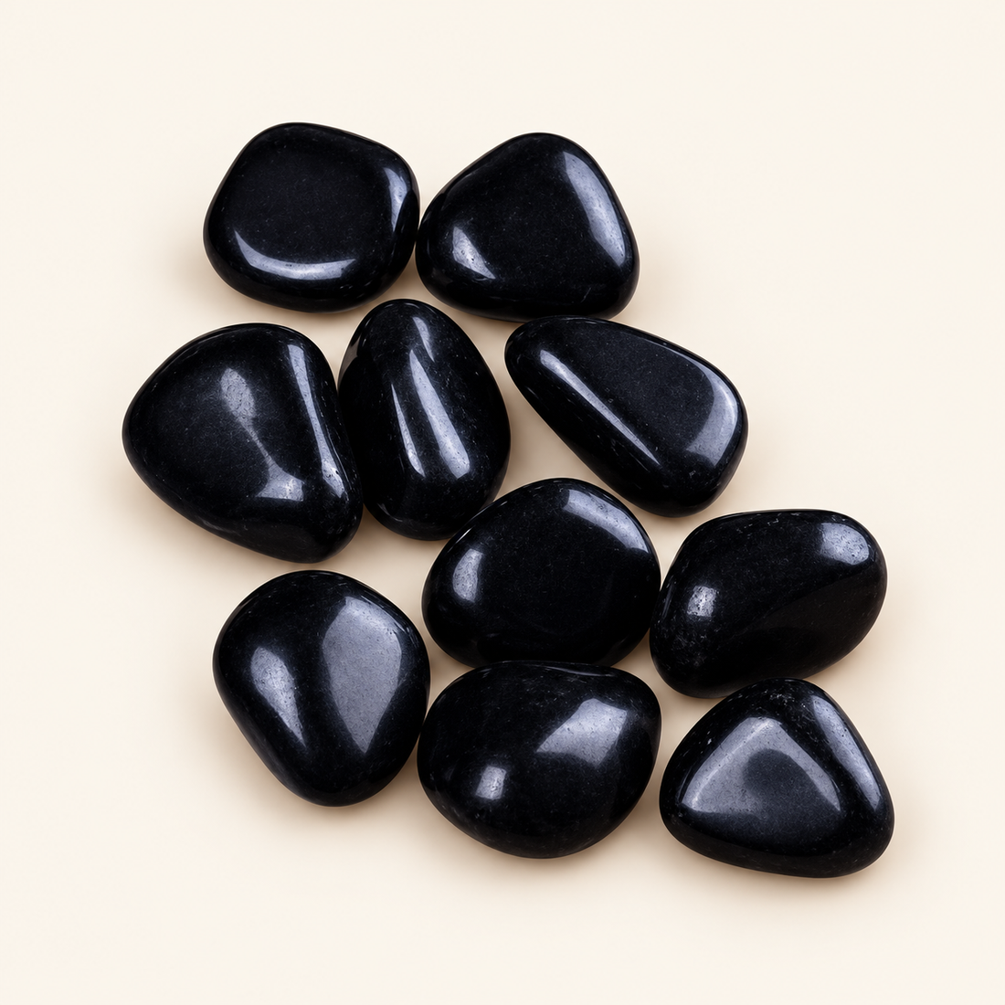 Black Obsidian tumbled stones with deep black shine on a soft ivory background