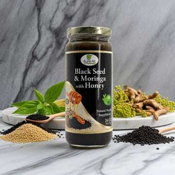 Jar of Black Seed & Moringa Herbal Honey with herbs on a white marble counter.