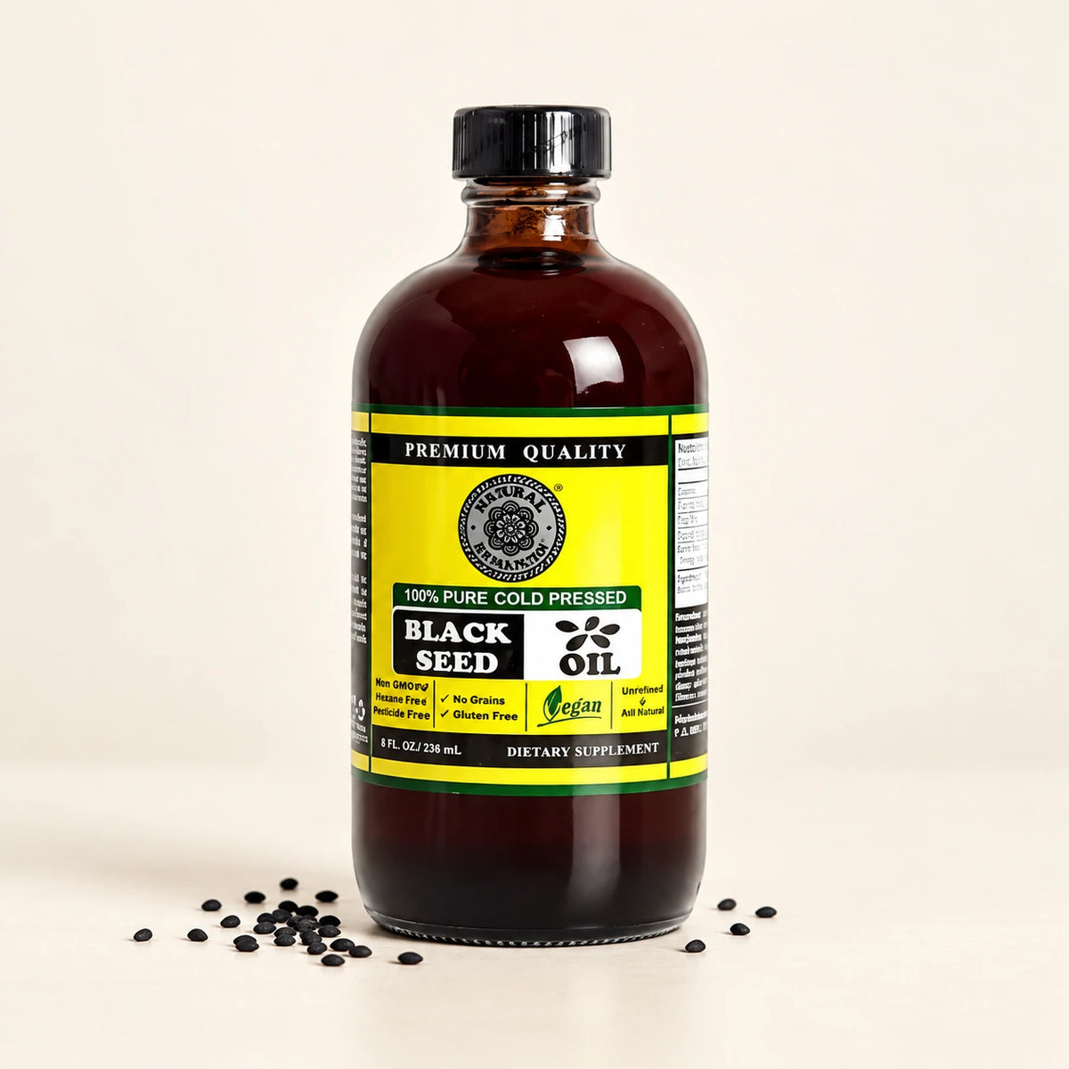 Black Seed Oil bottle with black seeds resting on an ivory surface.