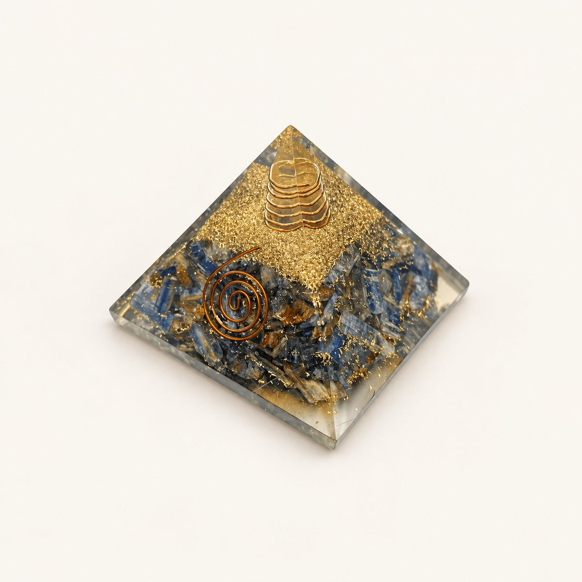 Blue Kyanite Orgone Pyramid with blue-gray kyanite chips and metallic details on a warm ivory background