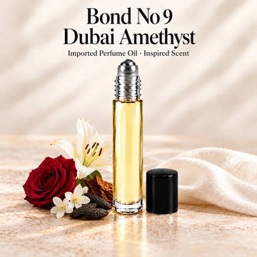 Bond No 9 Dubai Amethyst Perfume Oil in a slim glass roll-on bottle with a silver roller and black cap on an ivory stone surface.