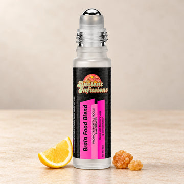 Ancient Infusions Brain Food Herbal Remedy Oil Focus & Clarity single roller bottle with botanical accents on a soft ivory stone background.