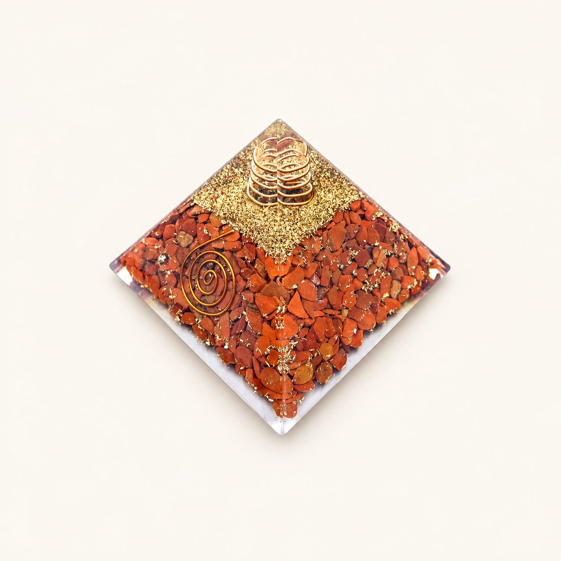 Carnelian Orgone Pyramid with warm orange carnelian chips and metallic details on a warm ivory background