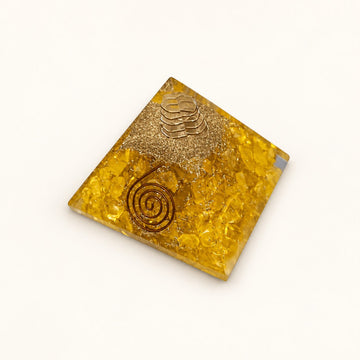 Citrine Orgone Pyramid with golden-yellow citrine chips and metallic details on a warm ivory background