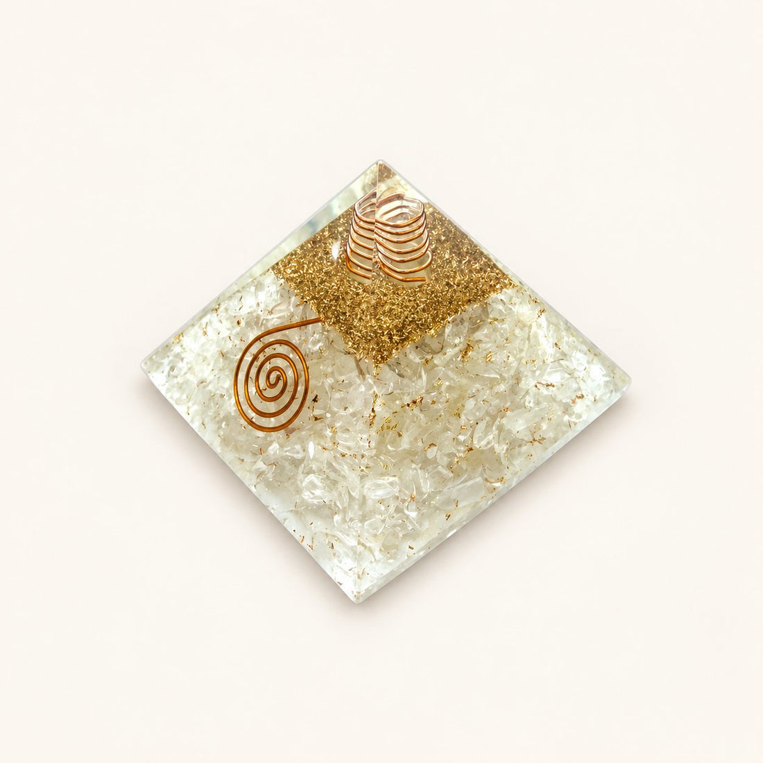 Clear Quartz Orgone Pyramid with translucent clear quartz chips and metallic details on a warm ivory background