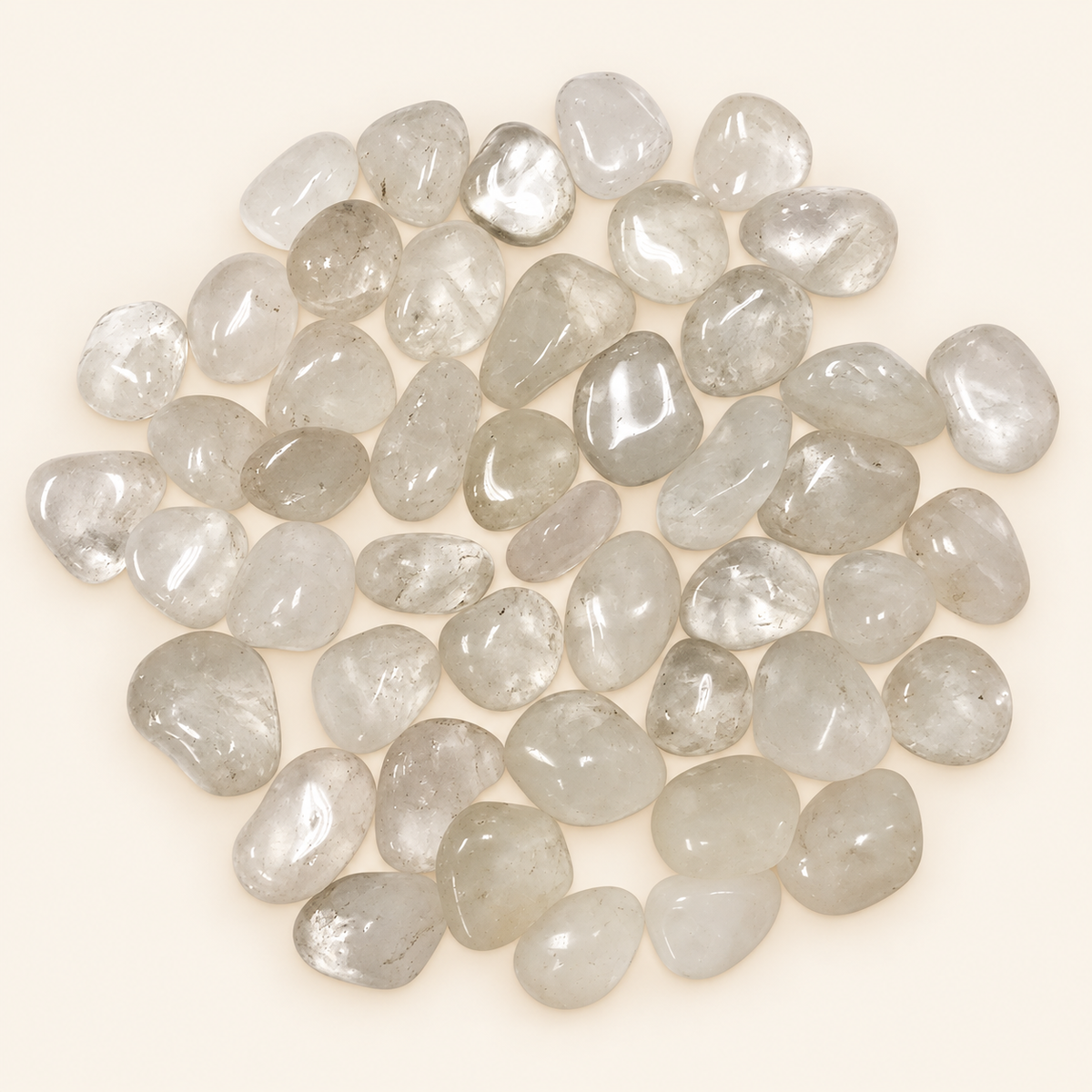 Clear Quartz tumbled stones with clear to milky translucence on a soft ivory background