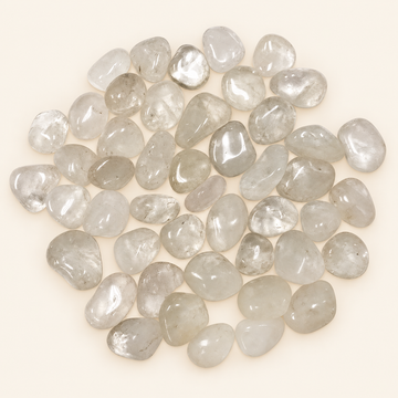 Clear Quartz tumbled stones with clear to milky translucence on a soft ivory background