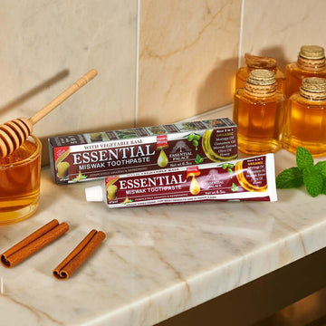 Essential Palace Miswak 5-in-1 Fluoride-Free Toothpaste with natural ingredients on marble counter with honey and cinnamon display