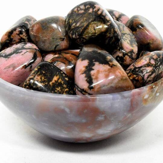 Polished Rhodonite tumbled stones showcasing their pink and black patterns, highlighting their emotional healing properties.