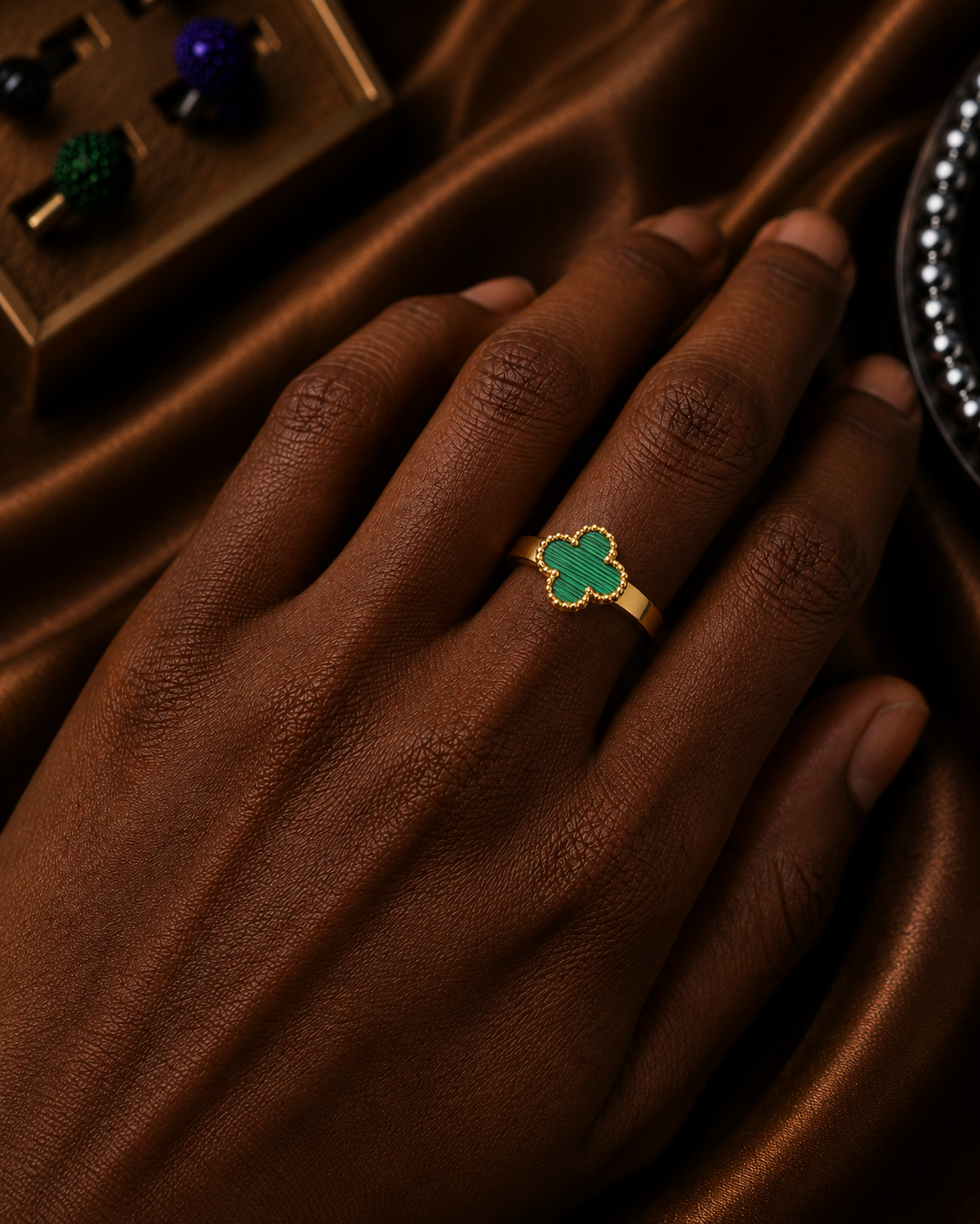 Green clover gold-tone ring worn on hand with an elegant polished finish.