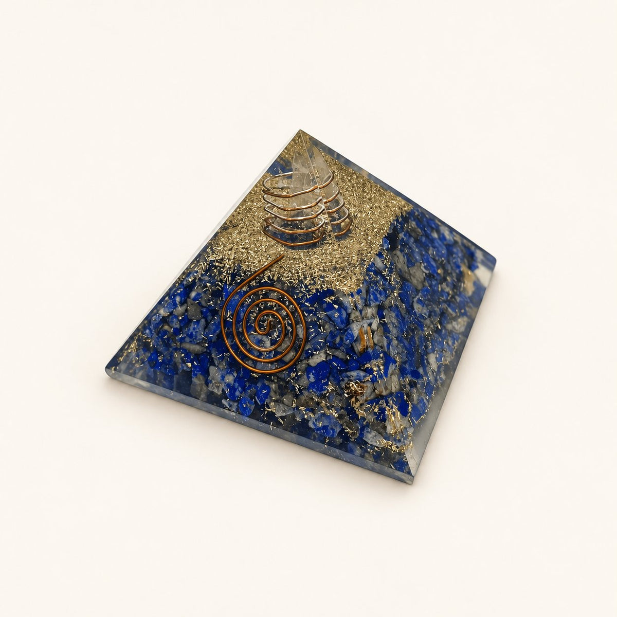 Lapis Lazuli Orgone Pyramid with deep blue lapis lazuli chips and metallic details on a warm ivory background