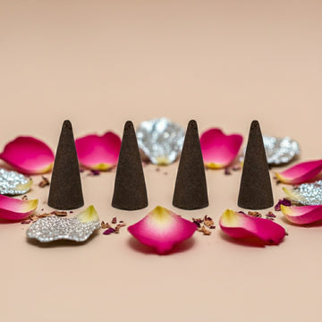 Paris Hilton Pink Rush Inspired Incense Cones on a beige surface with pink flower petals and decorative elements.