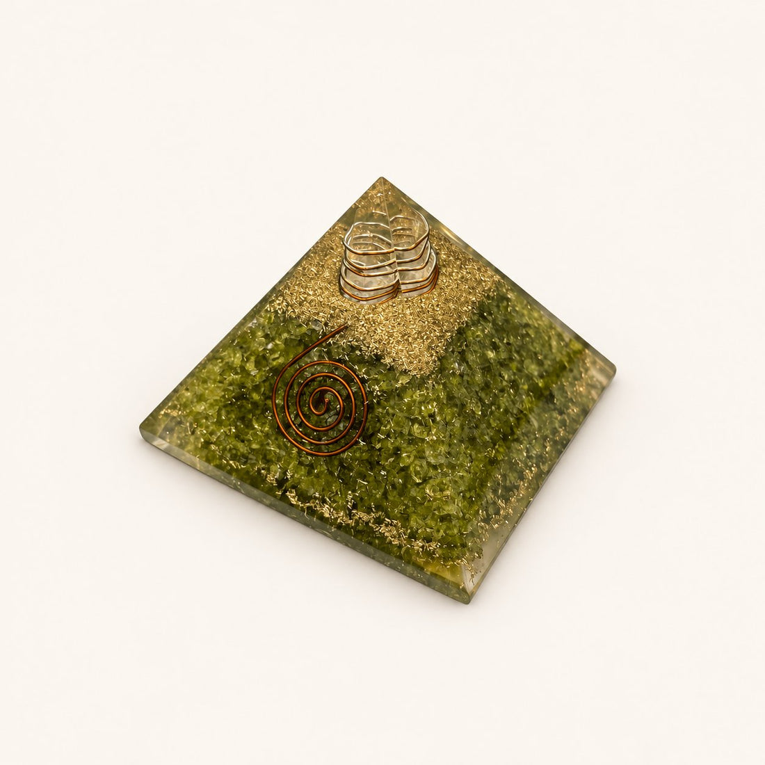 Peridot Orgone Pyramid with olive-green peridot chips and metallic details on a warm ivory background