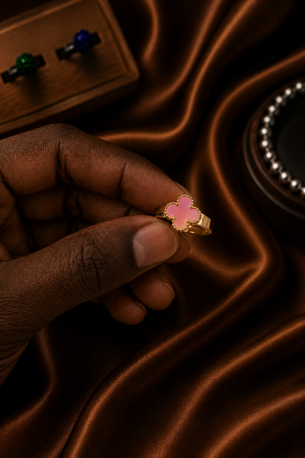 Close-up of pink clover gold-tone adjustable ring with polished band and delicate beaded detailing.