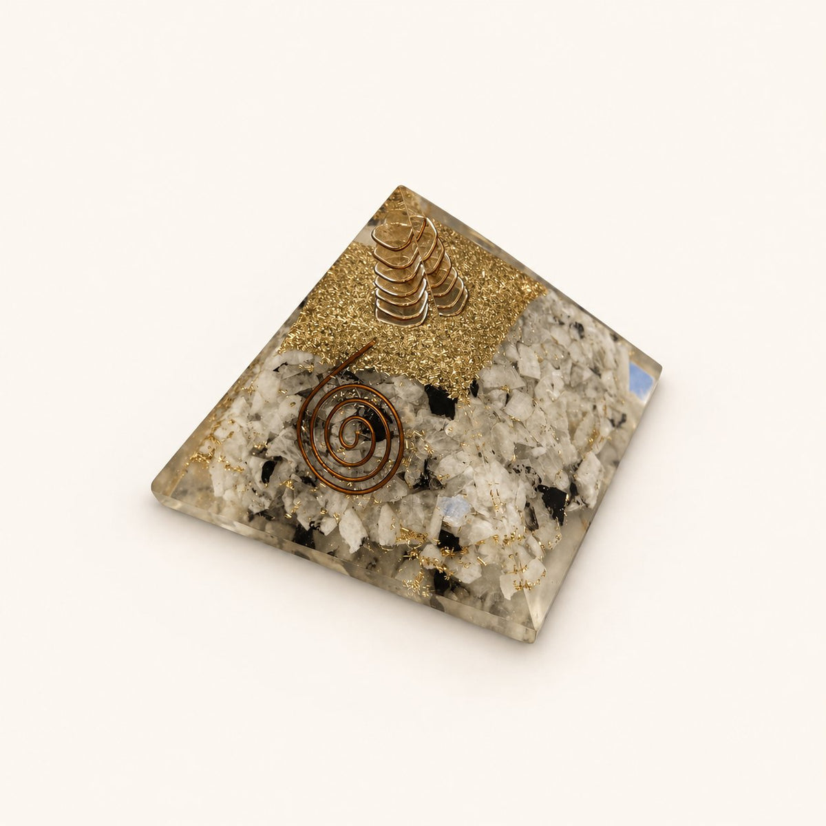Rainbow Moonstone Orgone Pyramid with pale rainbow moonstone chips with dark accents and metallic details on a warm ivory background