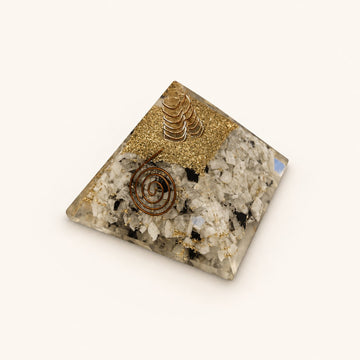 Rainbow Moonstone Orgone Pyramid with pale rainbow moonstone chips with dark accents and metallic details on a warm ivory background