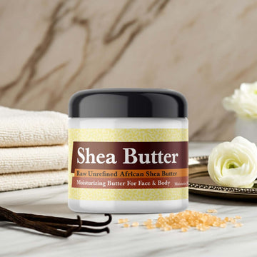 Imported Vanilla Musk Scented Shea Butter jar on a marble countertop with vanilla beans and flowers.