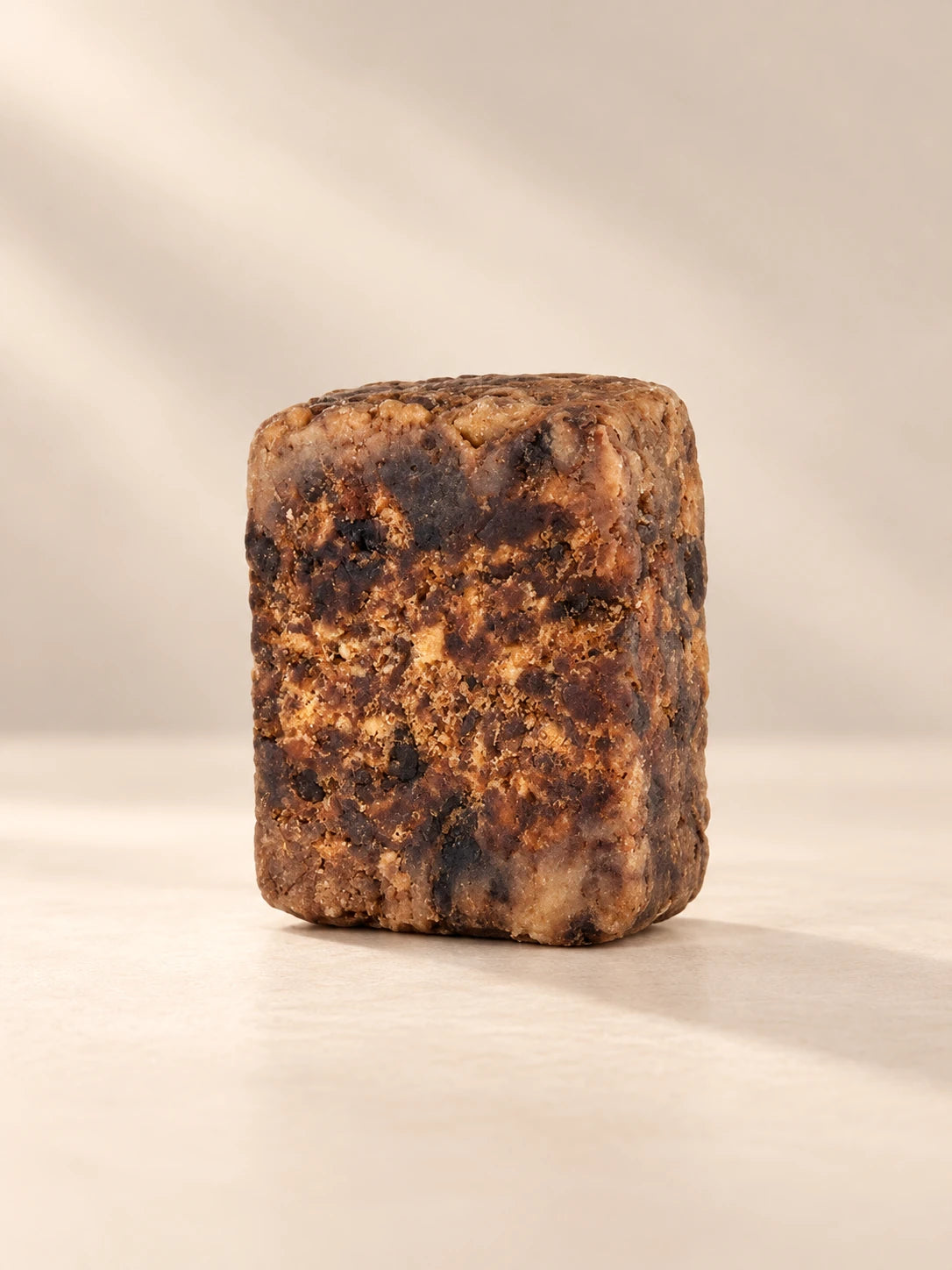 Raw Nigerian African Black Bar Soap by Ancient Infusions on a warm ivory background