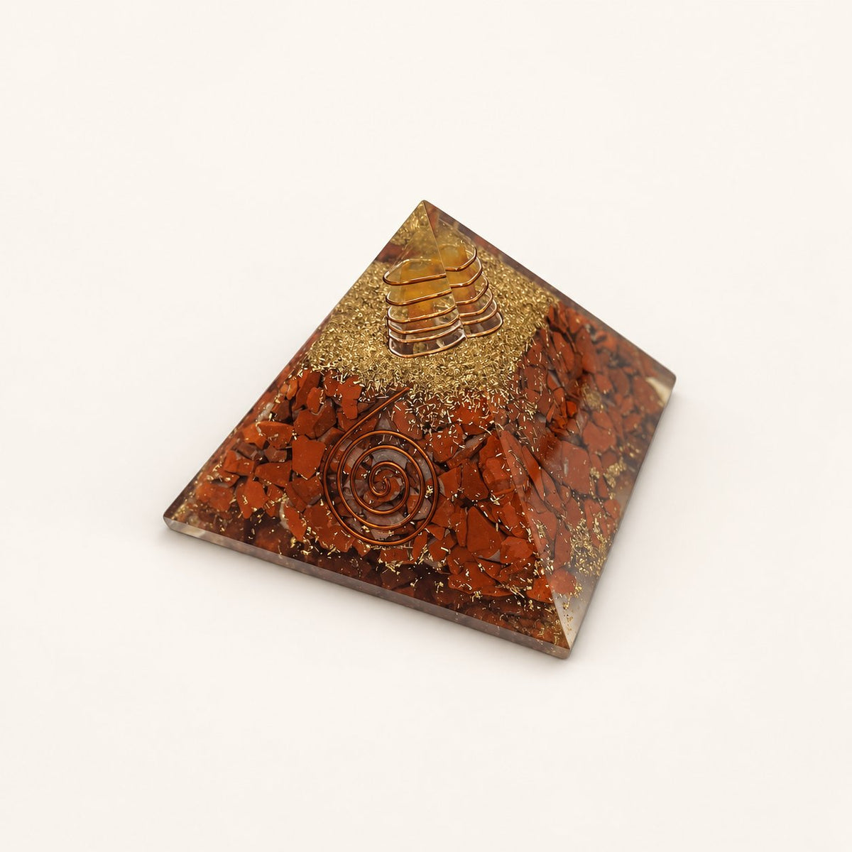 Red Jasper Orgone Pyramid with earthy red jasper chips and metallic details on a warm ivory background