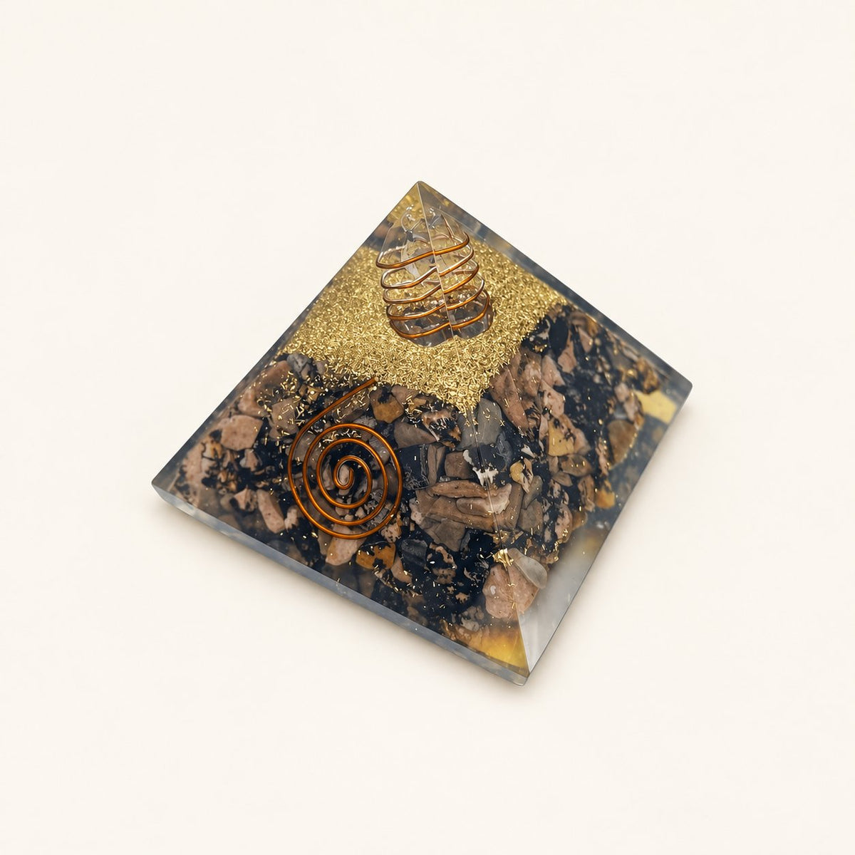 Rhodonite Orgone Pyramid with muted pink and charcoal rhodonite chips and metallic details on a warm ivory background