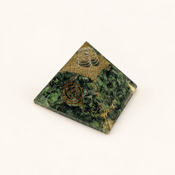 Ruby Zoisite Orgone Pyramid with green ruby zoisite chips with dark accents and metallic details on a warm ivory background