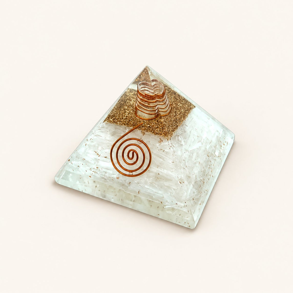 Selenite Orgone Pyramid with translucent white selenite chips and metallic details on a warm ivory background