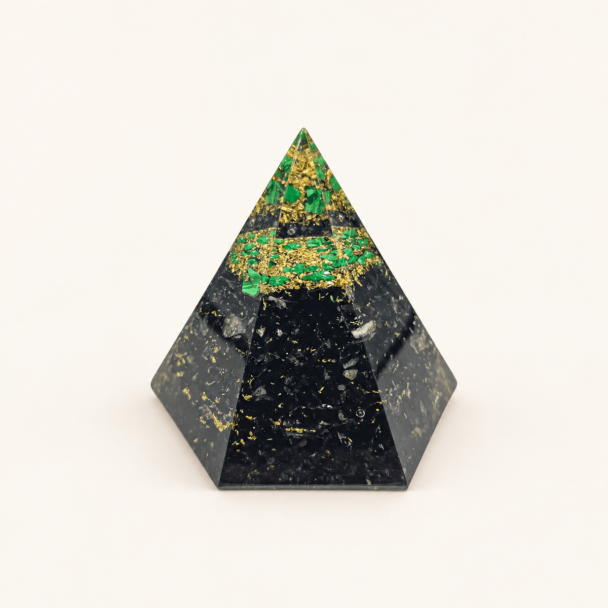 Shungite and Malachite Orgone Pyramid with contrasting black shungite and green malachite chips and metallic details on a warm ivory background
