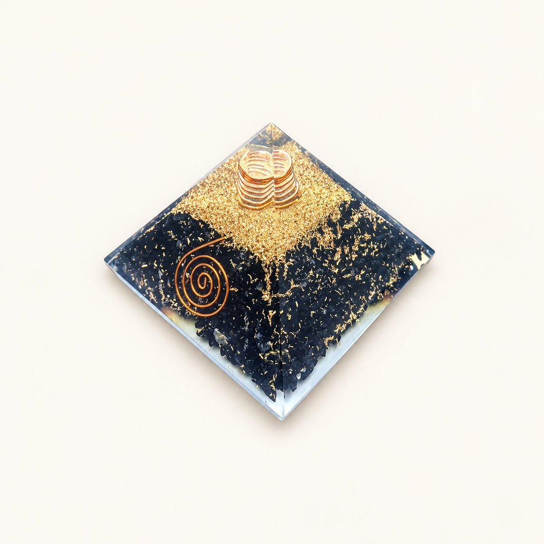 Shungite Orgone Pyramid with black shungite chips and metallic details on a warm ivory background