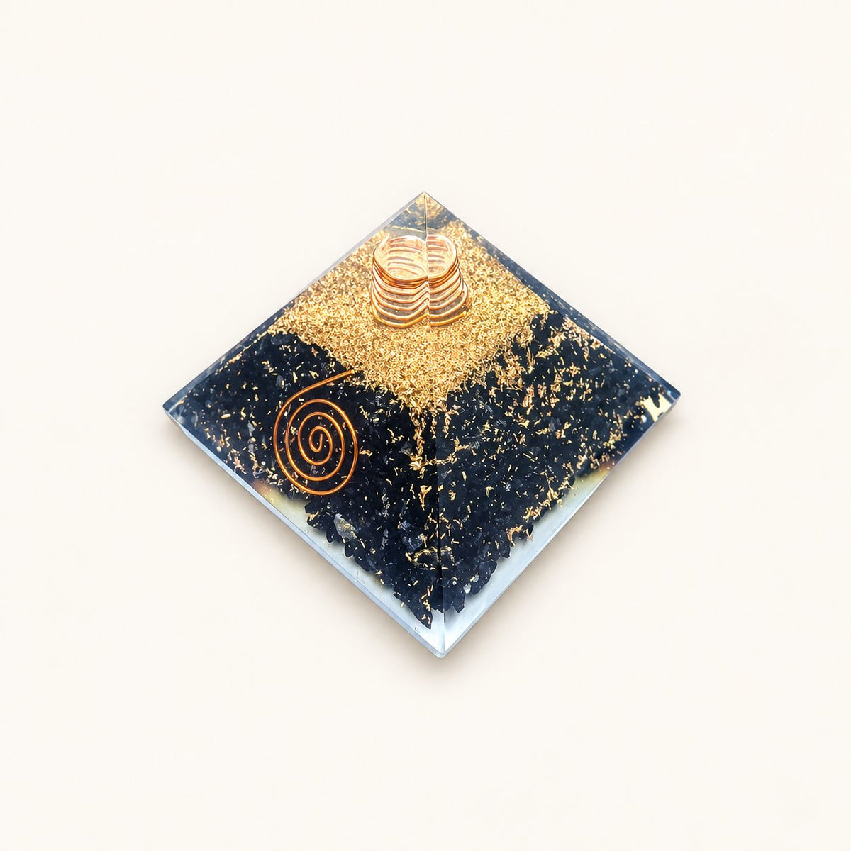 Shungite Orgone Pyramid with black shungite chips and metallic details on a warm ivory background