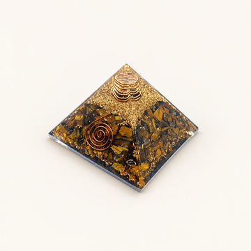 Tiger’s Eye Orgone Pyramid with golden-brown tiger’s eye chips and metallic details on a warm ivory background