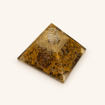 Yellow Jasper Orgone Pyramid with ochre-yellow jasper chips and metallic details on a warm ivory background